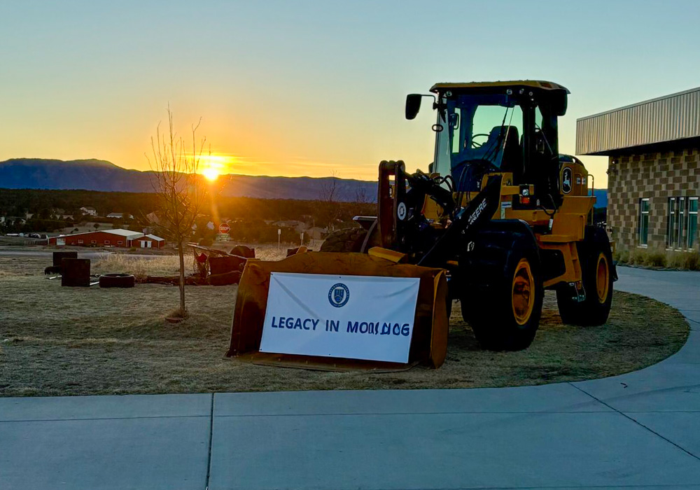 Excavator with a banner hanging from it with the words: "Legacy in Motion"